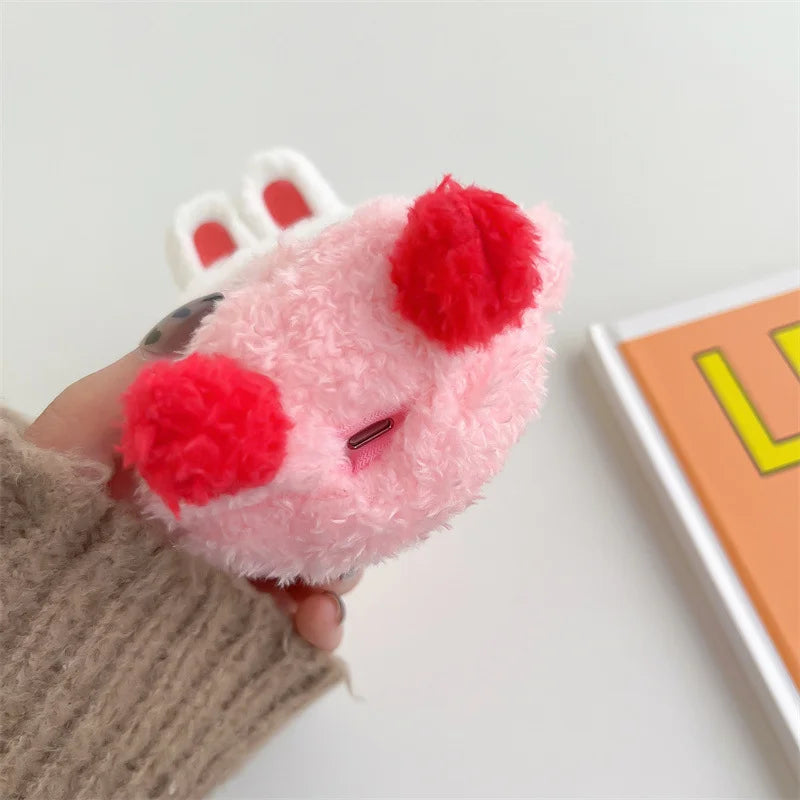 Pink plush toy with red accents held by a person wearing a brown sweater.