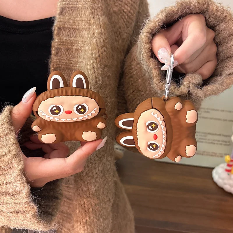 Two cute brown animal-shaped keychains held by a person wearing a beige coat.