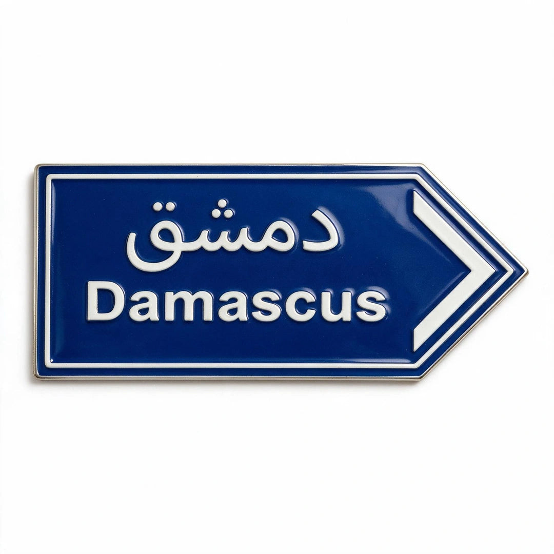 A blue and white enamel phone sticker shaped like a directional road sign pointing right, with the word 'Damascus' in English and Arabic script above it.