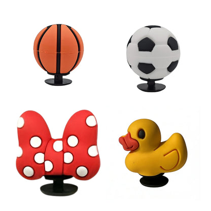 Four novelty croc charms shaped like a basketball, soccer ball, bow tie, and rubber duck on a white background.