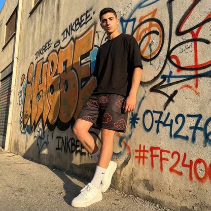 model leaning against wall wearing a black tshirt and black mesh shorts