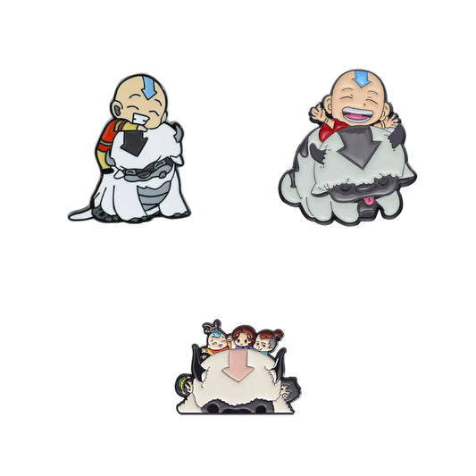 Three small cartoon enamel pins or charms featuring a bald child character in white clothing, shown on a plain white background.