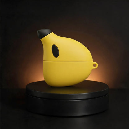 A yellow banana-shaped wireless earbud charging case with a black nose and side detail, displayed on a black circular pedestal against a dark background with warm light.