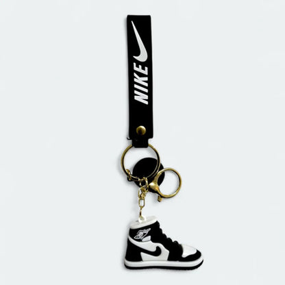 Nike keychain with a black strap and a shoe-shaped charm on a white background