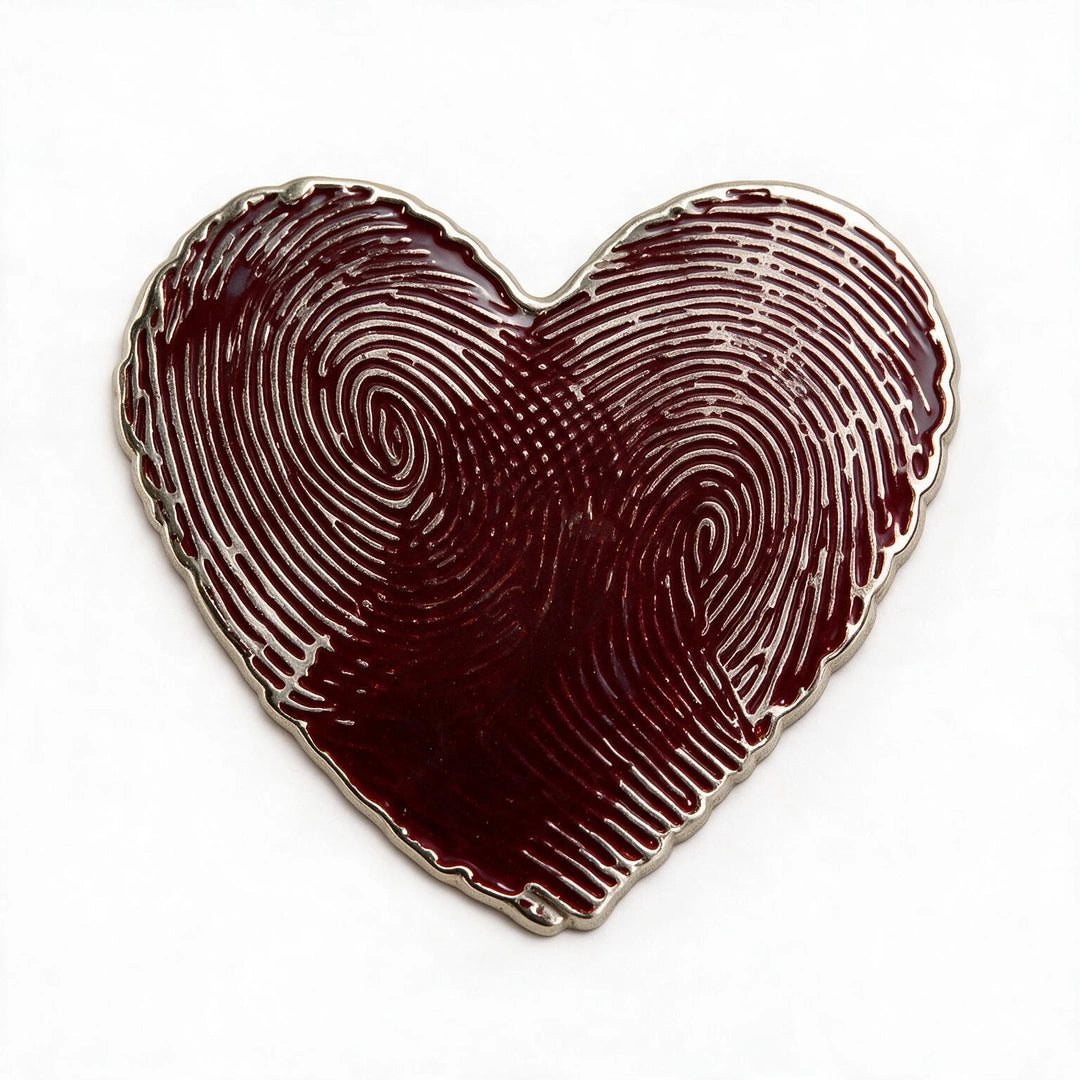 A heart-shaped enamel pin featuring a fingerprint pattern in deep burgundy red with a polished silver-tone metal border, set against a plain white background.