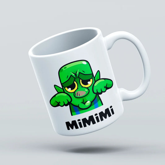 White mug with a green cartoon character and 'Mimimi' text on a light gray background