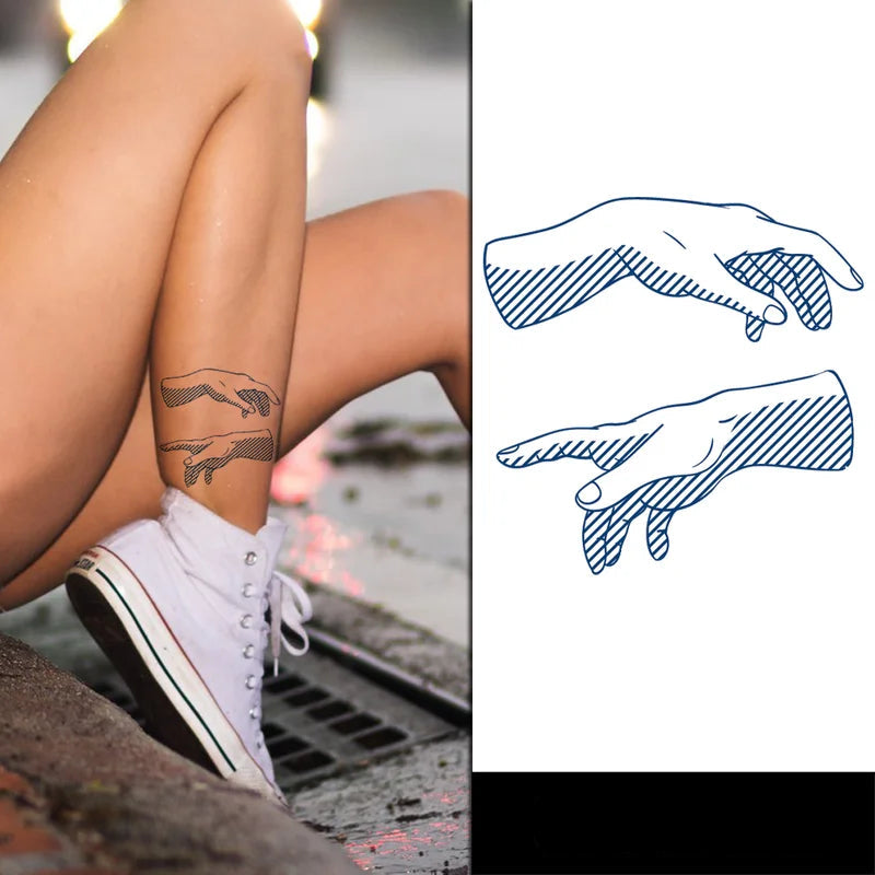 Person with a tattoo of two hands reaching towards each other, sitting on a curb.