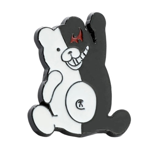 A cartoon bear-shaped pin or charm with a split black-and-white design, a small red horn detail on the forehead, and a small circular emblem on the belly, shown on a plain white background.