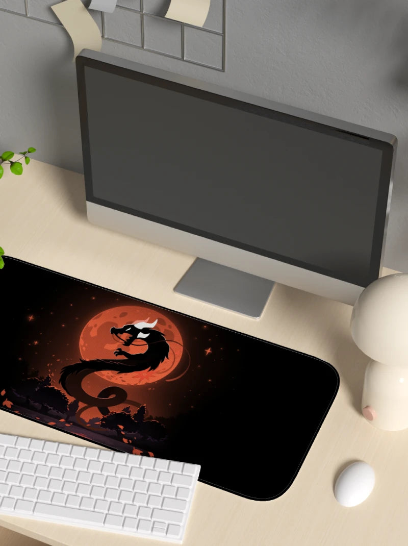 Desk setup with a computer monitor, keyboard, and mouse on a desk mat featuring a dragon design.