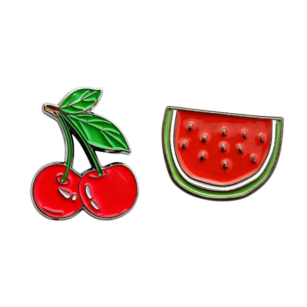 Two fruit-themed pins, one of cherries and the other of a watermelon slice, on a white background.