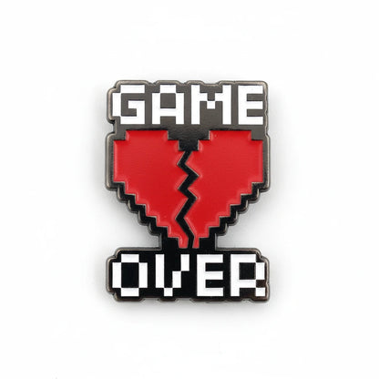 Pixelated 'GAME OVER' heart-shaped enamel pin on a white background