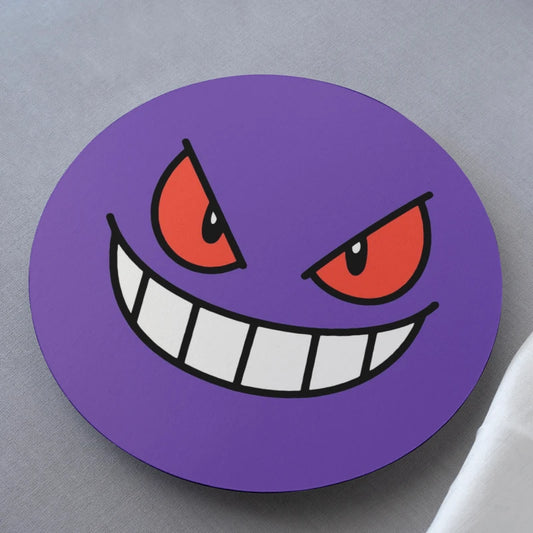 Circular purple coaster with a cartoonish face design on a gray surface