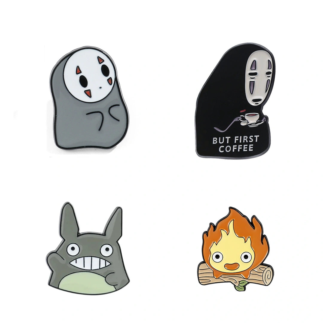 Four cartoon enamel pins arranged in a 2x2 grid on a white background, featuring characters from Studio Ghibli's animated films including No-Face from Spirited Away, But First Coffee from Coco, Totoro from My Neighbor Totoro, and Campfire from The Wind-Up Bird.