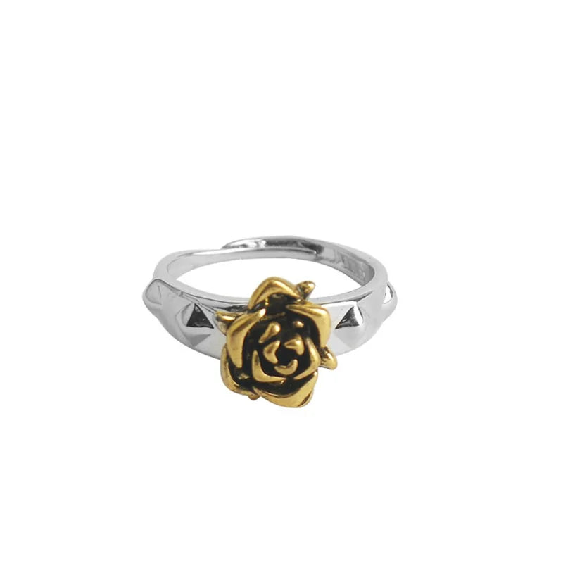 Silver ring with a gold rose design on a white background