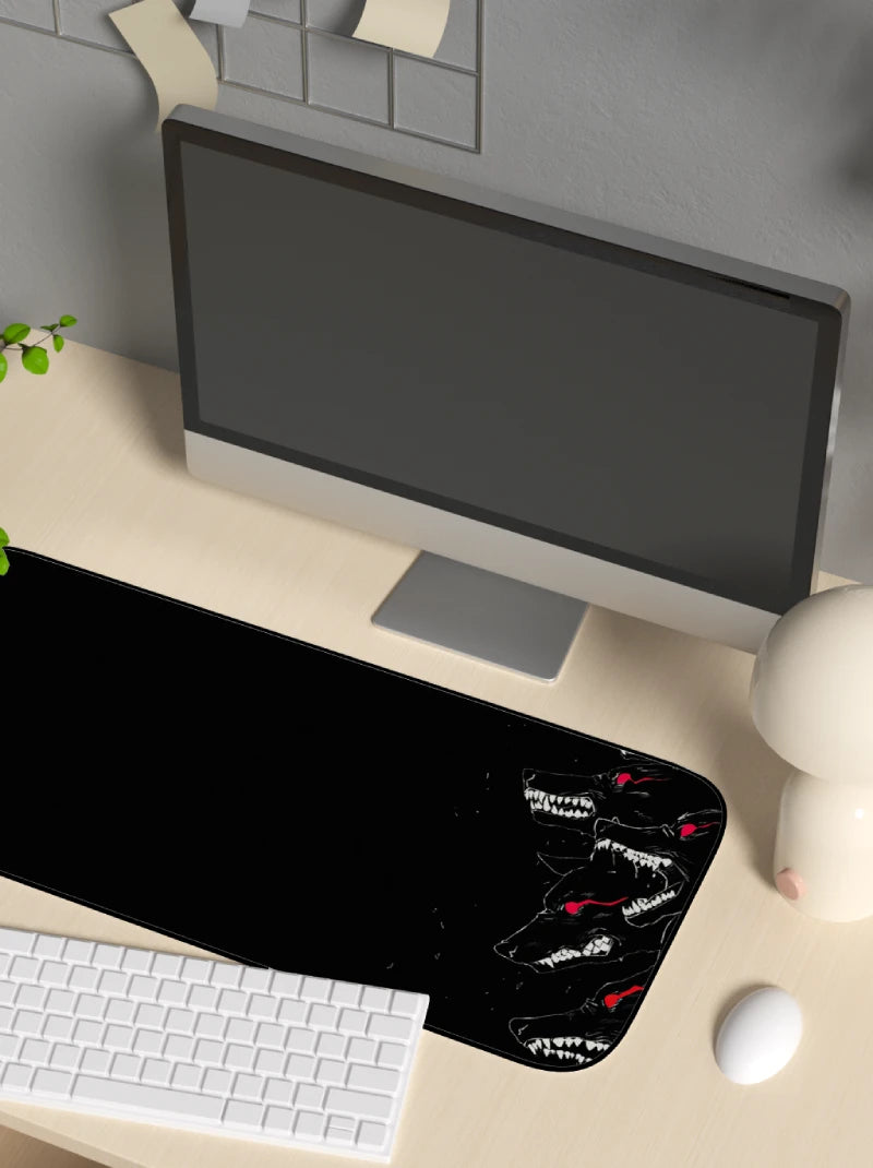 Black desk mat with white text on a beige desk with a computer setup and a mousepad with a hellhounds design