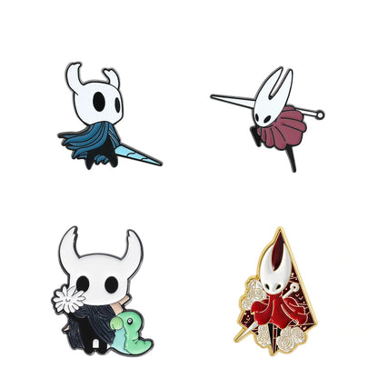 Four stylized character enamel pins arranged in a 2x2 grid on a plain white background. The characters resemble a small white creature with horns, one with a blue cape, one with a pink skirt, one holding a green creature, and one in a red robe with gold trim.