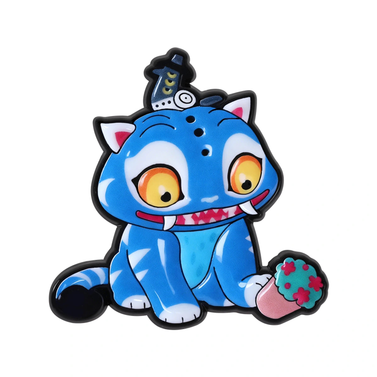 A blue cartoon cat character charm or patch with large yellow eyes, white paws and teeth, a black outline, a small hat on its head, and a pink cup in one paw, shown on a plain white background.