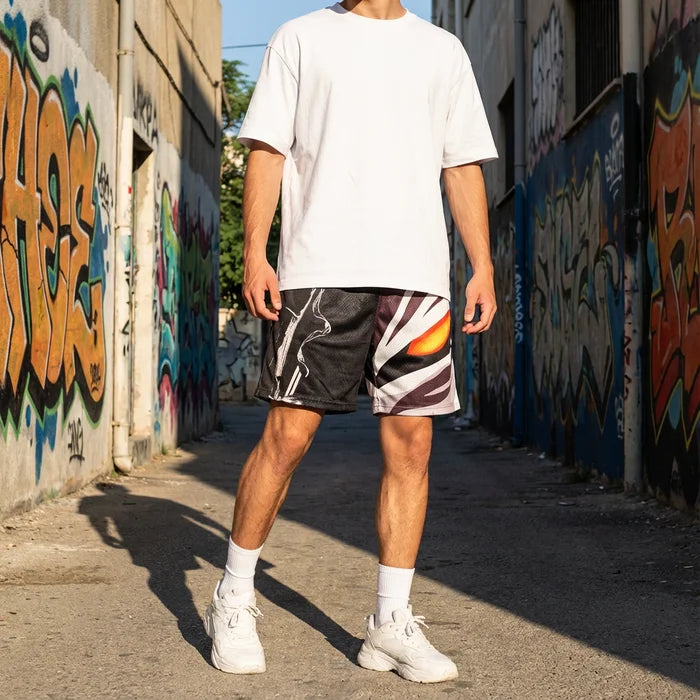 Person wearing a white t-shirt and patterned shorts standing in an alley with graffiti on the walls.