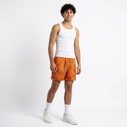 Person wearing a white tank top and orange patterned shorts on a white background