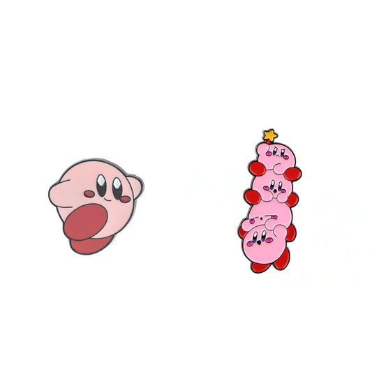 Two Kirby-themed enamel pins on a plain white background: one pin shows Kirby's face with its tongue sticking out, and the other shows a stacked, four-headed Kirby with a small yellow star on top.