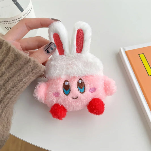 Plush toy shaped like a pink character with white fur and red accents held by a hand.