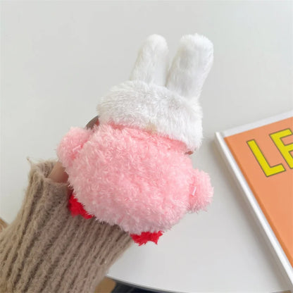 Plush bunny toy with a pink pom-pom held by a person wearing brown gloves on a light background.