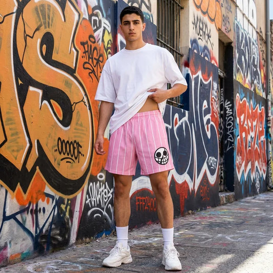 Person wearing a white t-shirt and pink shorts with a skull design, standing in front of a graffiti-covered wall.