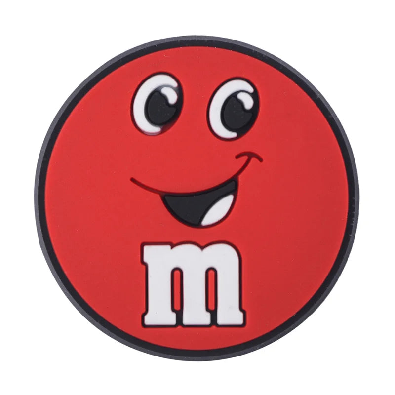 Red M&M croc charm with a black border on a white background