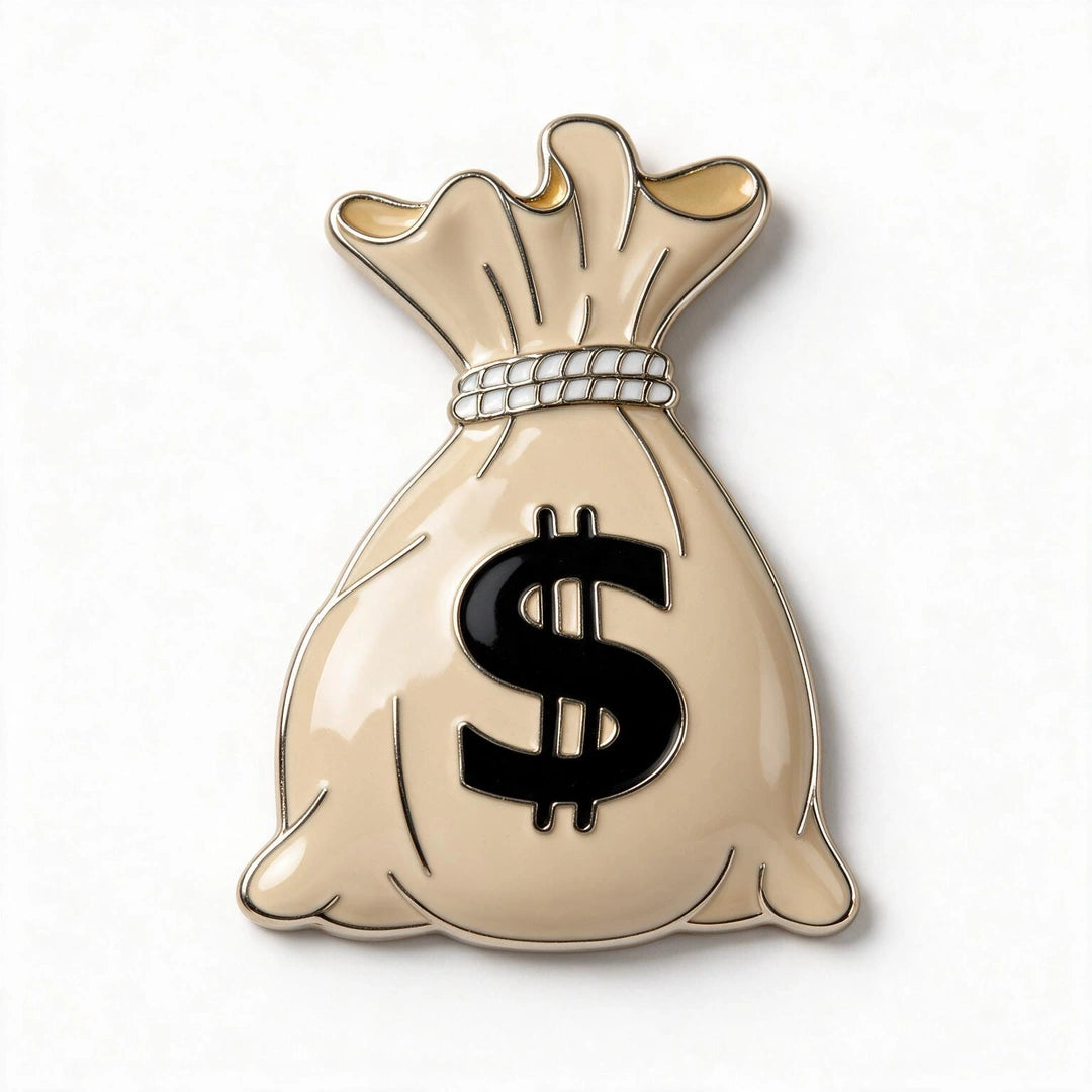 A money bag pin featuring a beige body with a black dollar sign, a white beaded rope detail, and gold-toned highlights, set against a plain white background.