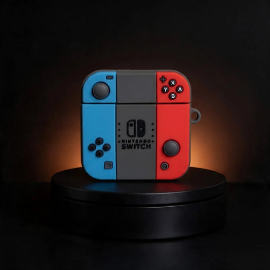 Nintendo Switch Joy-Con controller case for samsung galaxy buds and for apple airpods in blue, gray, and red, displayed on a black circular pedestal against a dark background with warm lighting.