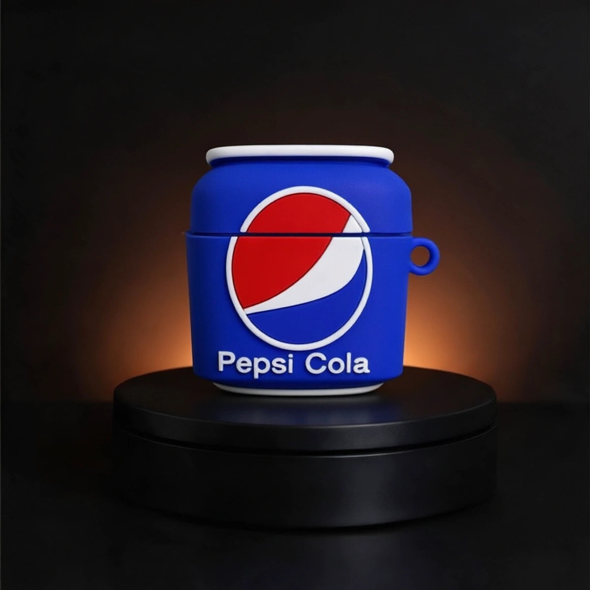 A blue AirPods case designed to look like a Pepsi-Cola can, featuring the red, white, and blue logo and 'Pepsi Cola' text, displayed on a black rotating platform against a dark background.
