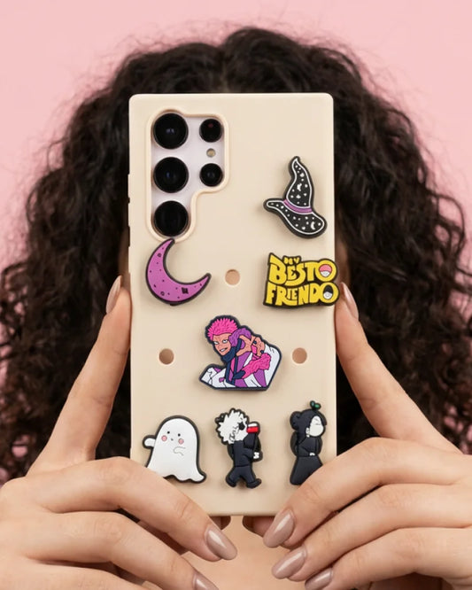 Phone case with various pins held by a person against a pink background