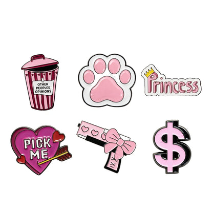 Six cartoon enamel phone sticker designs on a plain white background: a pink-and-white striped popcorn bucket with text, a pink paw print, a pink 'Princess' badge with a small gold crown, a pink heart with 'PICK ME' and an arrow, a pink-and-white pistol with a bow, and a pink dollar sign.