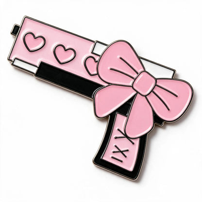 A novelty enamel phone sticker shaped like a pink handgun with black outlines, three heart cutouts on the slide, and a large pink bow wrapped around the handle, shown on a plain white background.