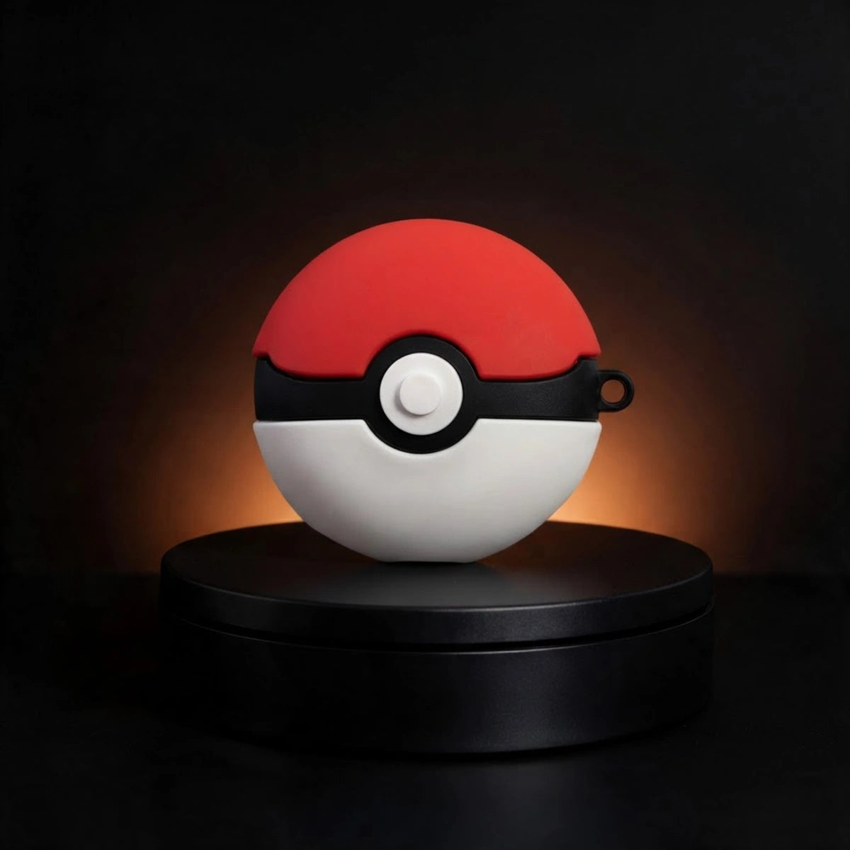 A red and white spherical device with a black horizontal band and central white button, styled like a Pokéball, displayed on a black circular pedestal against a dark background with warm light glow.