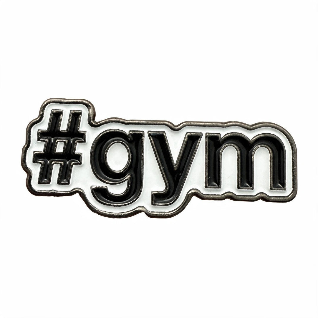A close-up of a white enamel pin with black lettering that reads '#gym' on a plain white background.