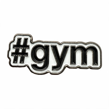 A close-up of a white enamel pin with black lettering that reads '#gym' on a plain white background.