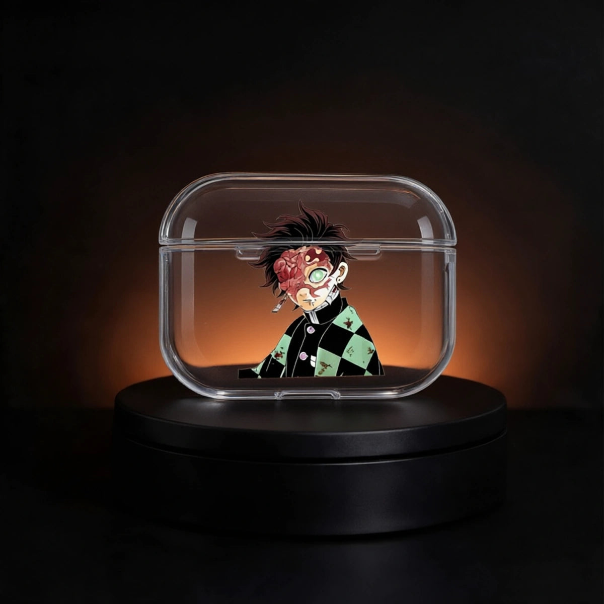 A clear rectangular protective case with rounded corners, shown on a black rotating display base against a dark background with warm orange lighting. The case contains a small anime-style character figure with messy black hair, a red scarred face, and a green-and-black checkered outfit.