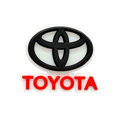 Black Toyota logo croc charm with red text on a white background