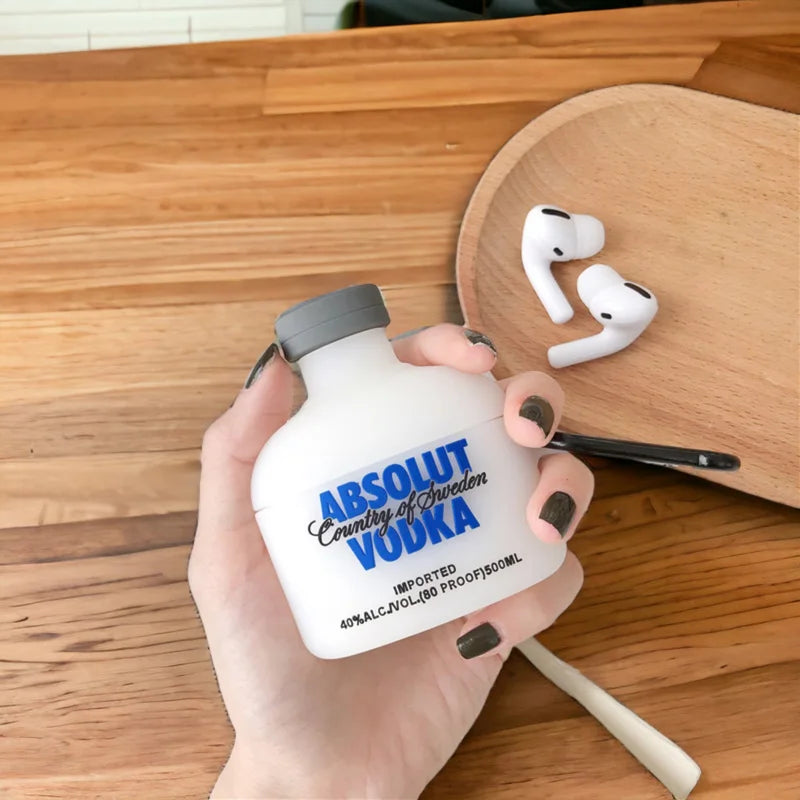 Hand holding a bottle-shaped object with 'Absolut Vodka' branding on a wooden surface.