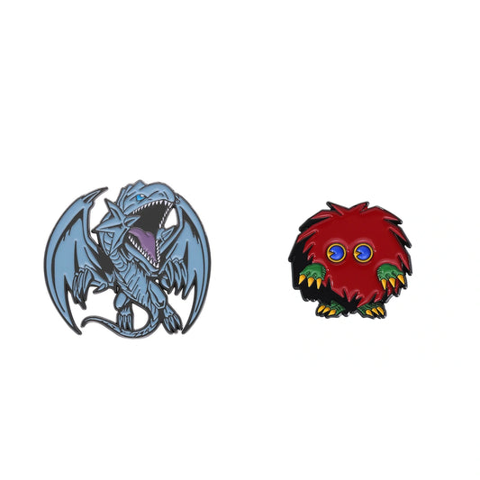 Two small fantasy character enamel pins on a plain white background: a blue dragon on the left and a red furry monster with blue eyes and green/yellow accents on the right.